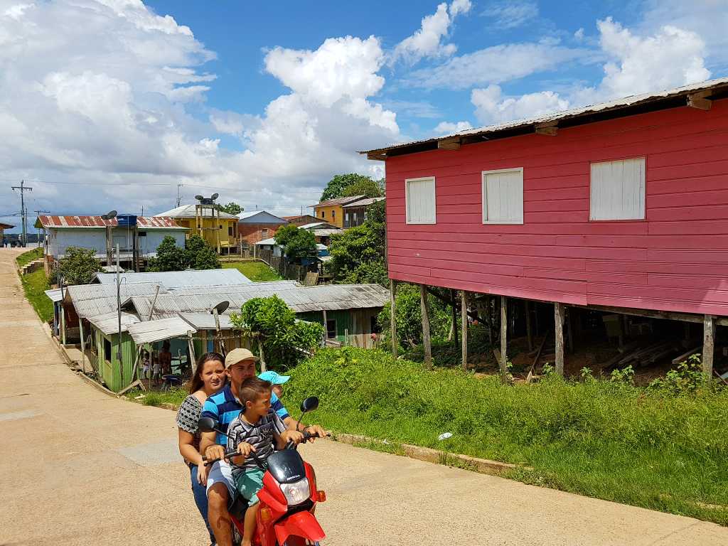 Dorf am Amazonas mit Motorradfahrern.